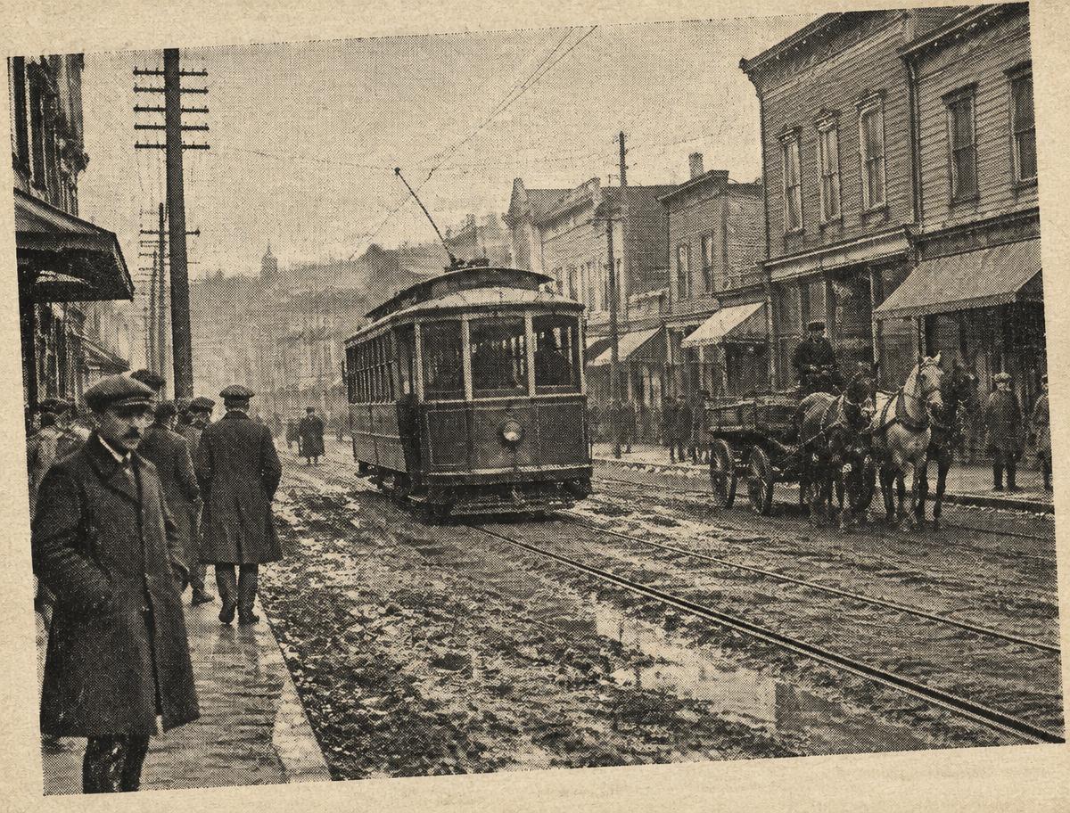 An early streetcar on a muddy Portland street, horses and pedestrians in the foreground